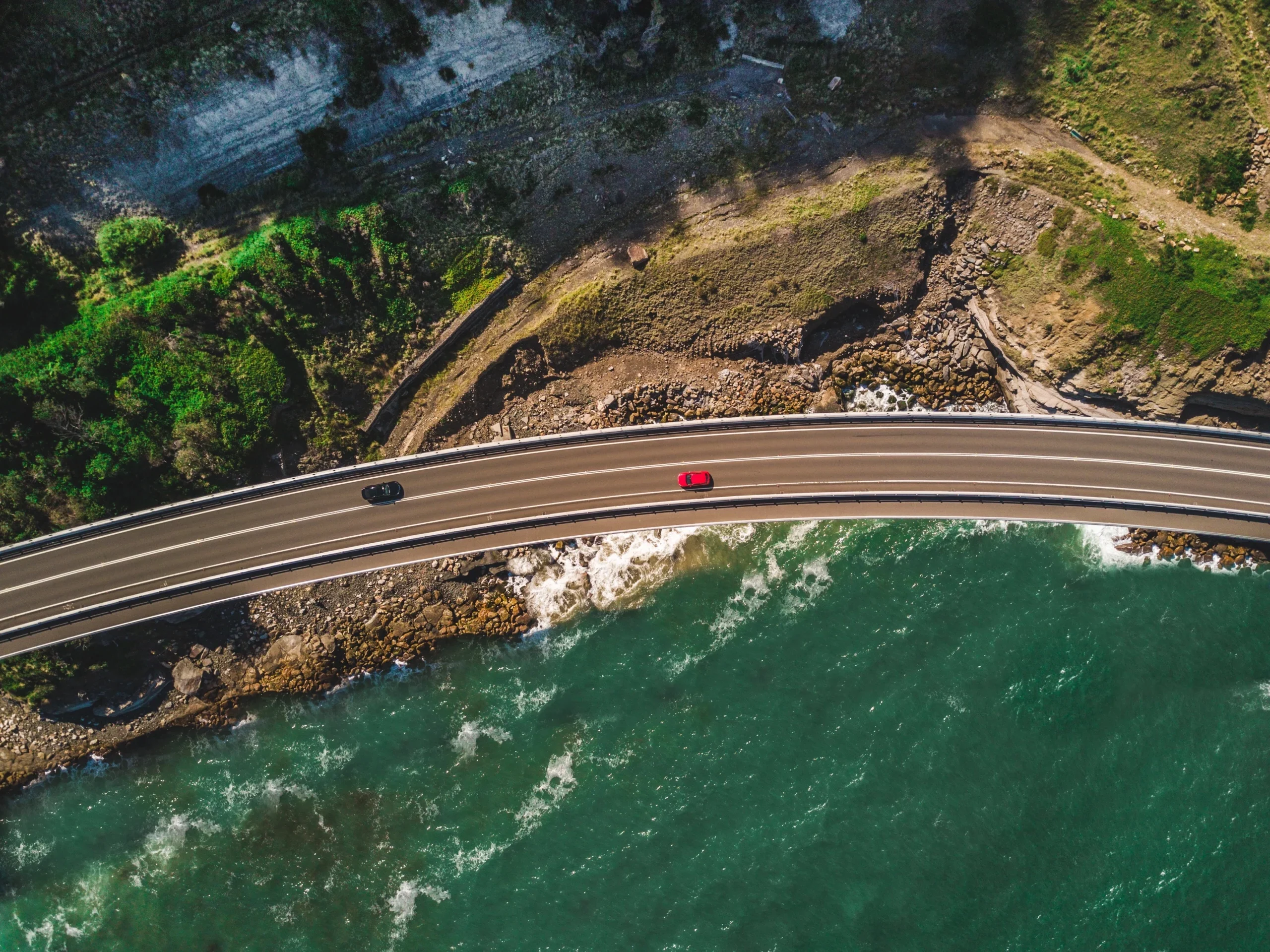narrow-curvy-road-with-cars-alongside-green-mountains